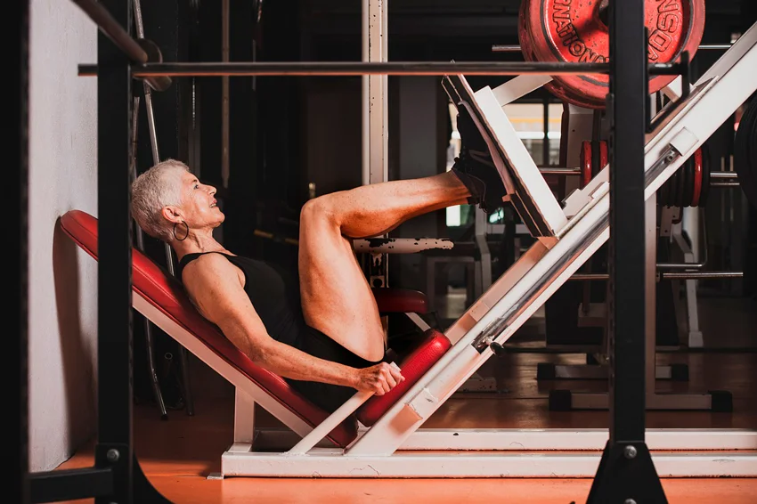 mujer ejercitando las piernas en maquina ejercicios multifuncional gym
